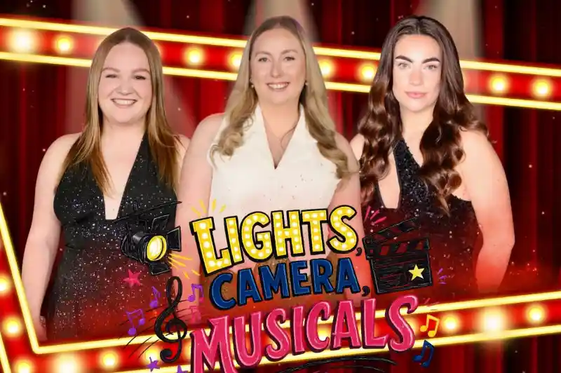 Three women pose together in front of a bright, red stage curtain with a marquee that reads "Lights, Camera, Musicals." They are dressed in sparkly outfits, each with a different hairstyle, and smiling at the camera. The background features colorful musical notes and film elements.