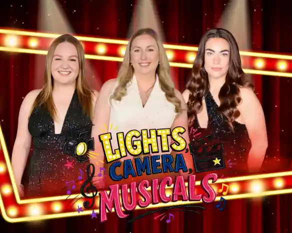 Three women pose together in front of a bright, red stage curtain with a marquee that reads "Lights, Camera, Musicals." They are dressed in sparkly outfits, each with a different hairstyle, and smiling at the camera. The background features colorful musical notes and film elements.