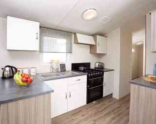 A modern kitchen displaying a stove, sink, and refrigerator, illustrating a practical area for cooking and cleaning.