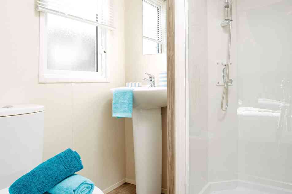 A well-organized bathroom containing a toilet, sink, and shower, with contemporary fixtures and a soothing colour palette.