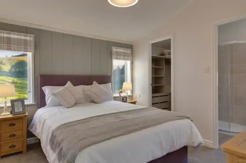 Spacious bedroom with a king-size bed, countryside views through plaid-curtained windows, and an open closet with a walk-in shower.