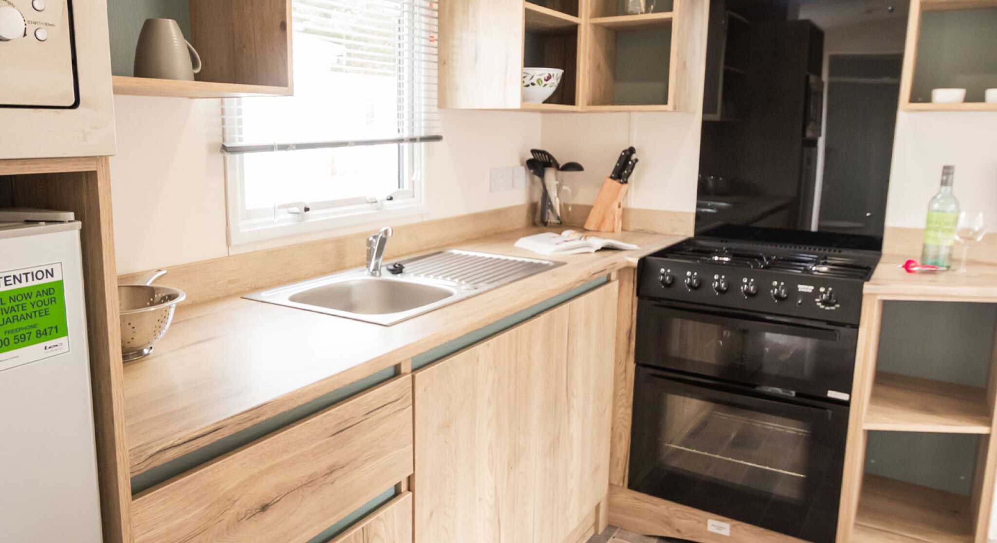 A well-equipped modern kitchen displaying a stove, oven, sink and refrigerator, highlighting essential cooking appliances.