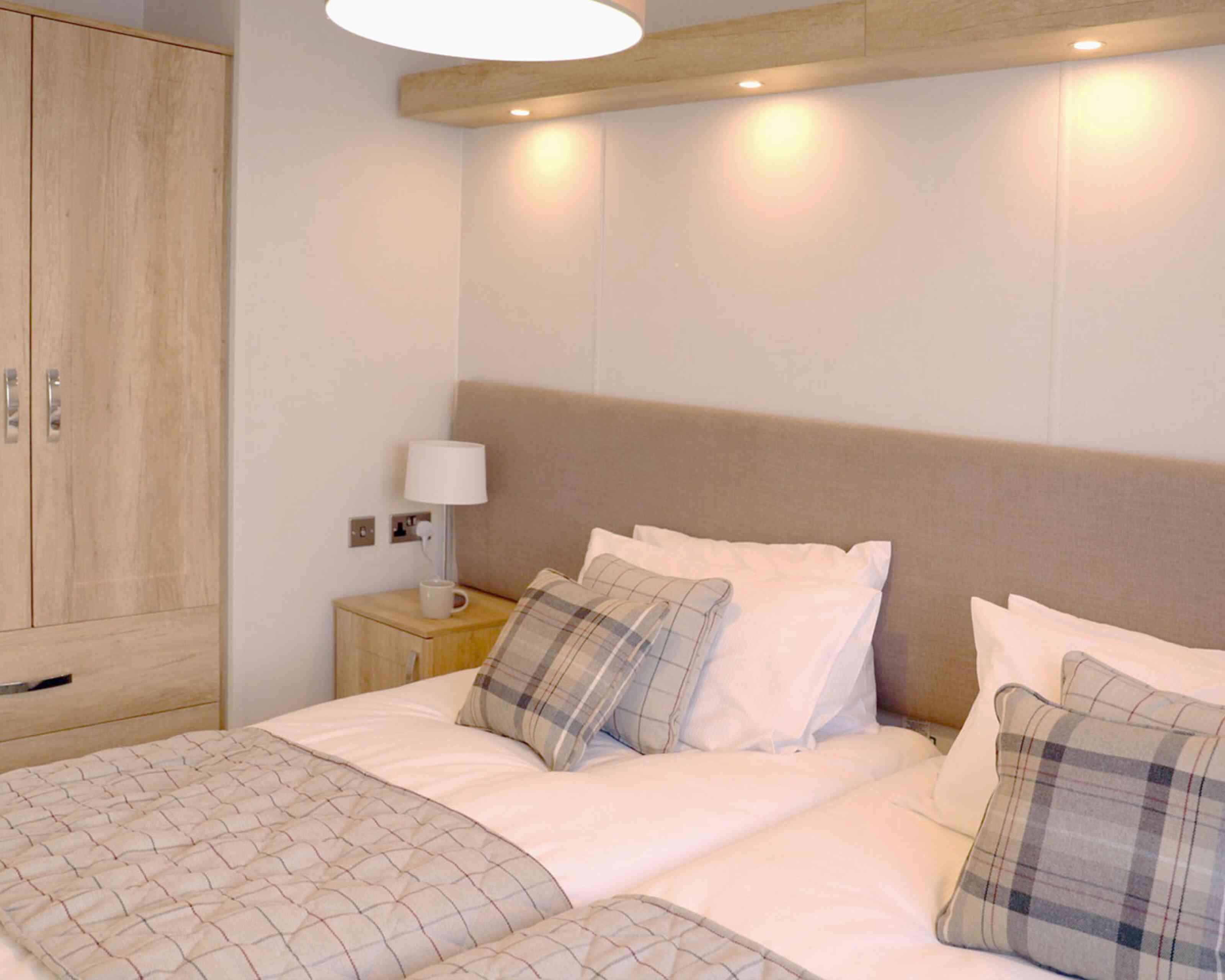 A well-furnished bedroom showcasing two beds and a wardrobe, designed for comfort and practicality.