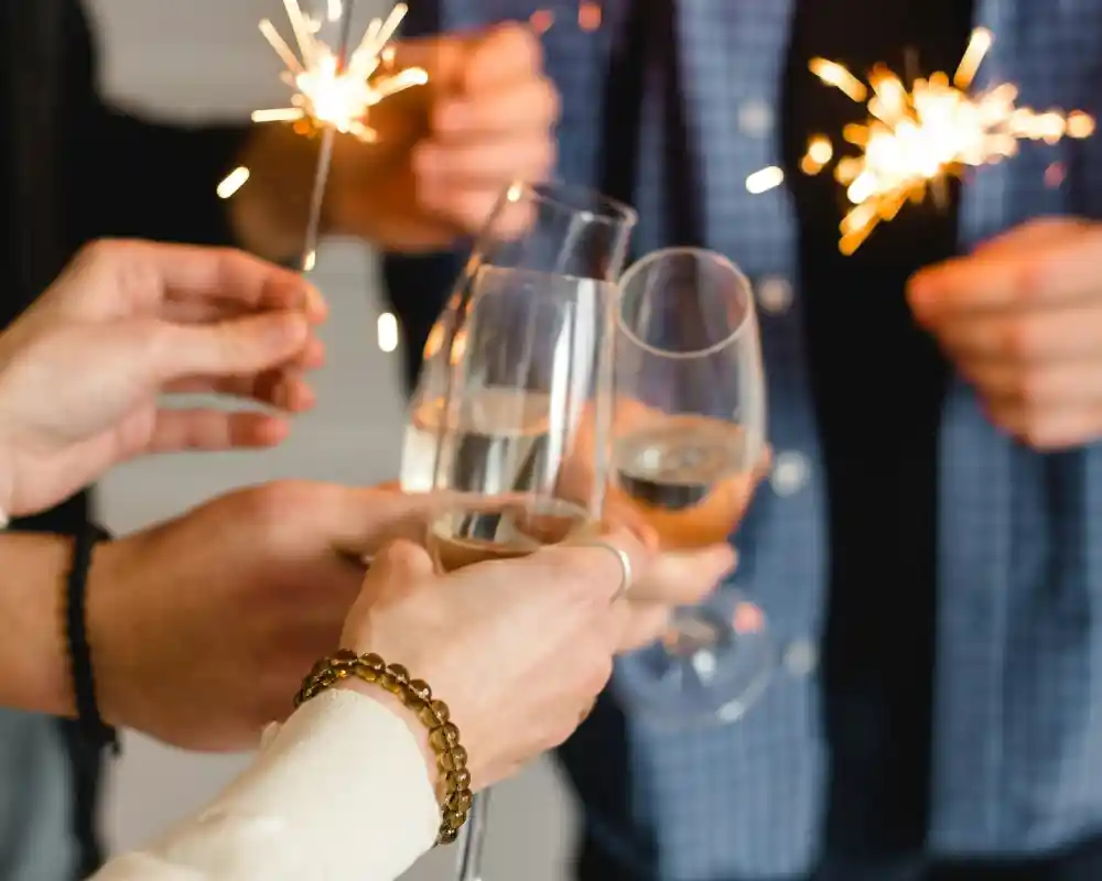 Champagne glasses clinking together while holding sparklers, celebrating a festive occasion.