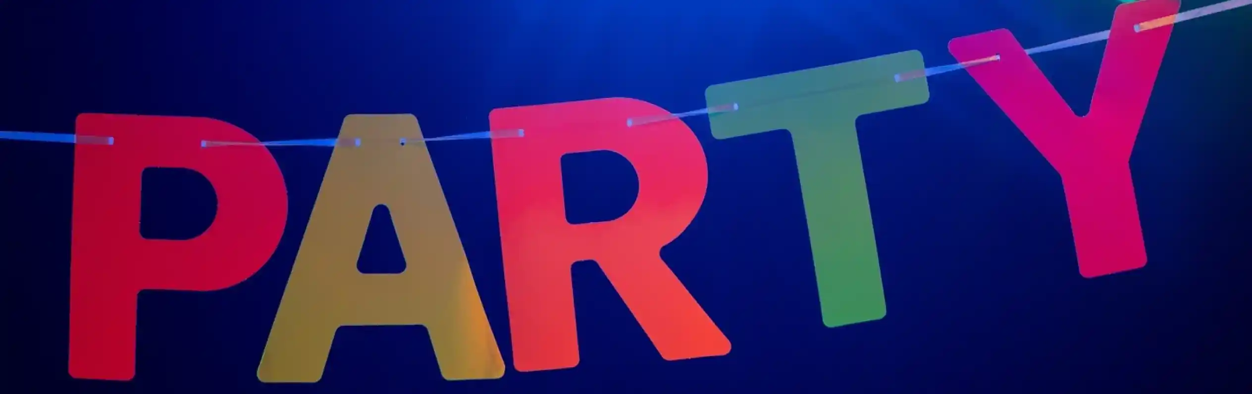 Colorful letters spelling "PARTY" are strung across a dark background, illuminated by vibrant blue and purple lights.